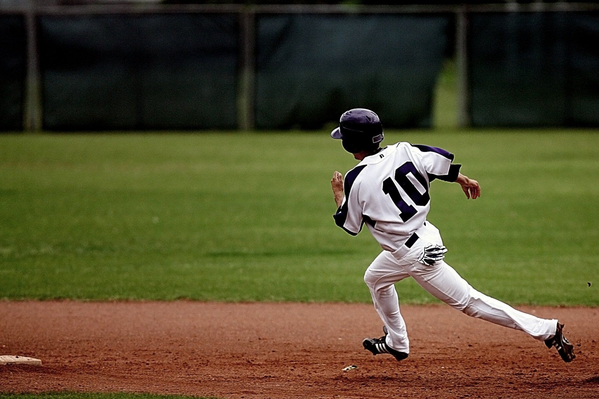 Baseball player in white uniform sprinting across the infield toward the right during a game